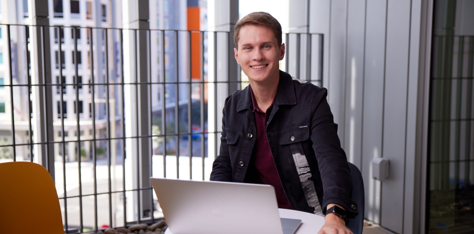 Thunderbird undergraduate student works on his laptop from a balcony at global headquarters