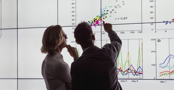 Two people inspect data on a large screen