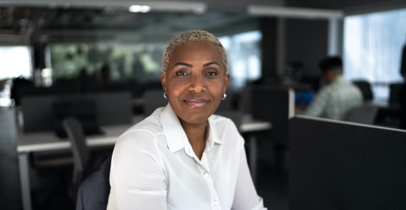 A woman looks at the camera while sitting at her office desk