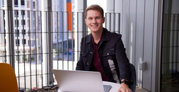 Thunderbird undergraduate student works on his laptop from a balcony at global headquarters