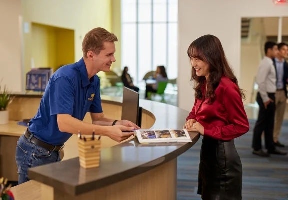 Image of Thunderbird student at the information desk speaking with a Campus Ambassador
