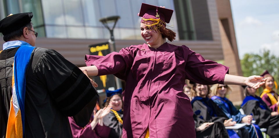 A robed students walks on stage at ASU West Campus' commencement ceremony