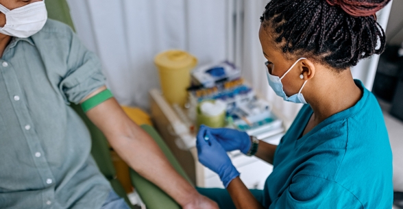 Image of a medical professional preparing to draw blood from a patient.