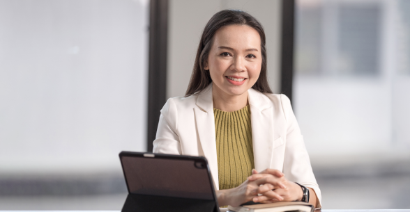 Image of a middle aged asian woman at a laptop in an office setting.