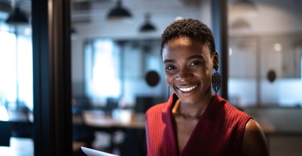 Image of a smiling woman with a tablet in an office.