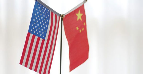 The United States and Chinese flags hang next to each other on a white background