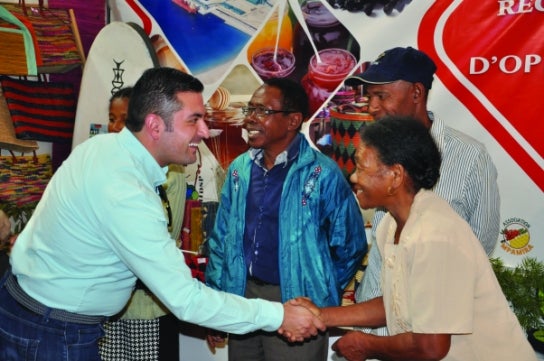 A Thunderbird student smiling and shaking hands with a woman in Madagascar during the Global Challenge Lab