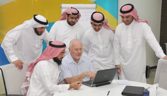 Image of men huddled around a laptop during a consultation meeting